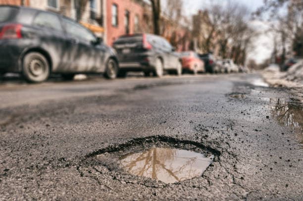 Bache en la calle con agua reflejando el cielo